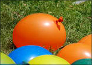 Fun activities for toddlers: Throwing water balloons. Orange water balloon in the grass.