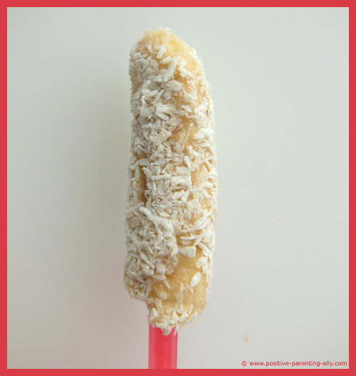 Healthy frozen snack with no sugar: banana ice lolly / popsicle rolled in coconut.