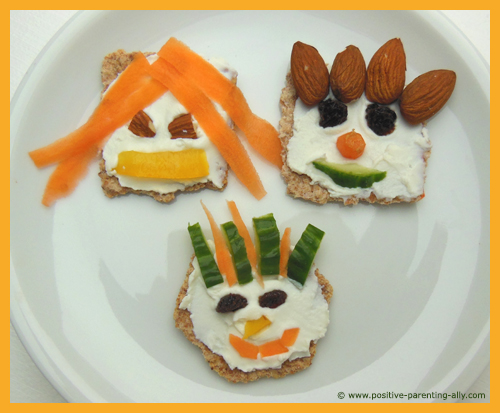 Funny kids snacks: funny faces on crackers with carrot, cucumber, raisins, almonds and cream cheese