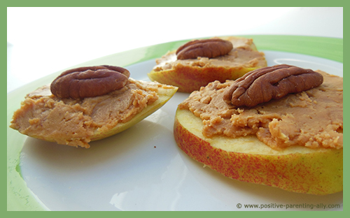 Healthy recipes for kids with apple slices, peanut butter and pecan nuts.