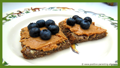 Quick easy snack for kids: peanut butter on whole grain bread topped with blueberries.