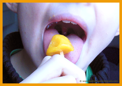 Kid eating healthy mango popsicle. Fruit popsicle recipe.