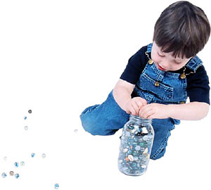 Tidying games: Boy picking up his marbles. 