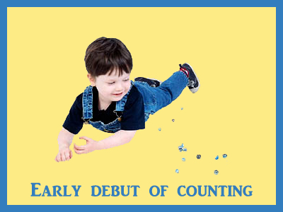 Little boy on his stomach next to marbles. New skill of counting.