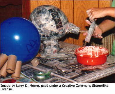 Kids making fun crafts for kids in terms of paper mache on balloons.