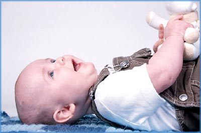 Baby lying on his back with a toy in his hands.