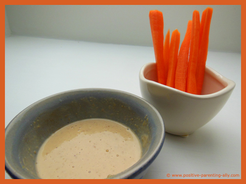 Thin carrot sticks with peanut butter dip as healthy foods for kids.
