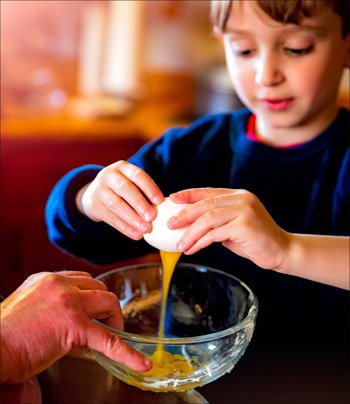 Child baking and breaking an egg.