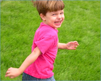 Little boy running on grass in the game of Mother Hen and the Colored Eggs.