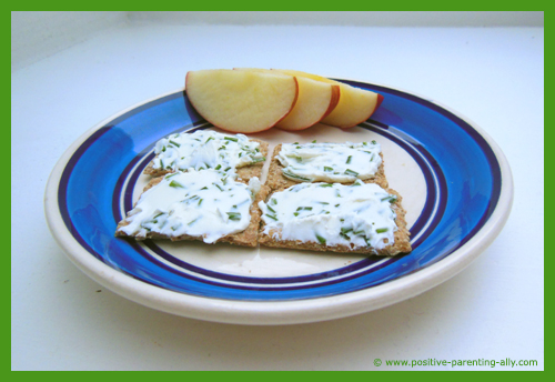 Crackers with creme cheese mixed with chive as a healthy quick snack for kids.