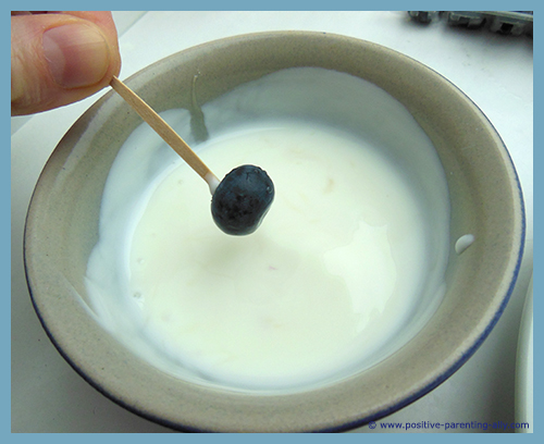 Dipping blueberries in yoghurt.
