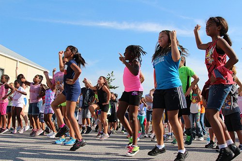 Group exercises for kids in school yard.