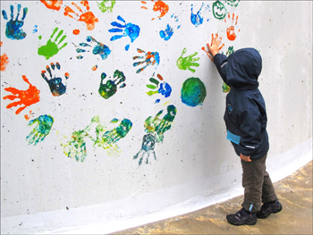 Colorful handprints in paint on white wall.