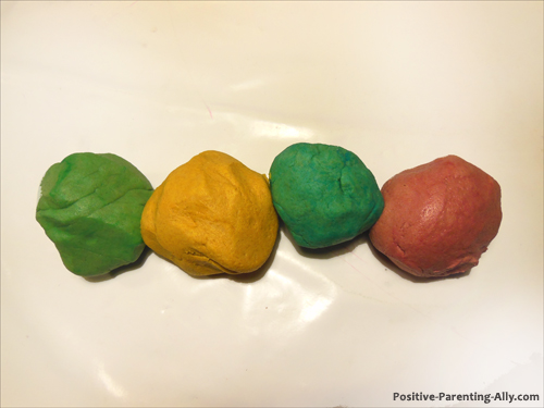 Homemade play doh in red, green, blue and yellow colors.