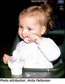Little toddler girl eating with a spoon.