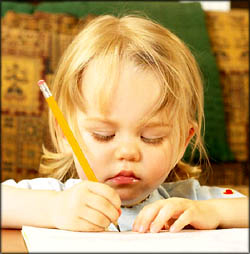 Little toddler girl drawing with a crayon on paper.