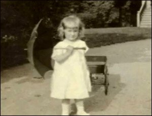 Old photo of Mary Ainsworth as little girl holding an umbrella.