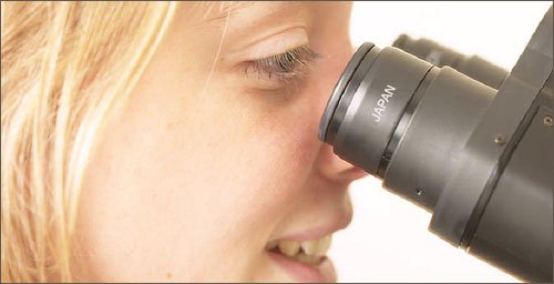 Girl looking through microscope: Great kids science websites on biology.