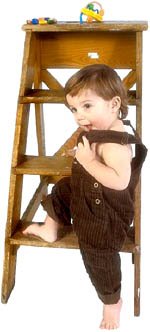 Little toddler girl about to climb small wooden ladder.