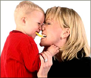 Fun toddler games: Mom and son intimate moment: rubbing noses, biting the same bisquit.