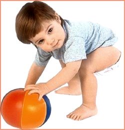 Toddler reaching down for soft ball.