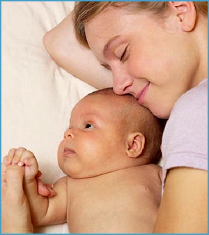 Mom lying down next to baby in bed. Close contact with baby.