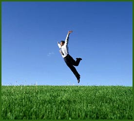 Freedom: Man jumping in joy in grass field.