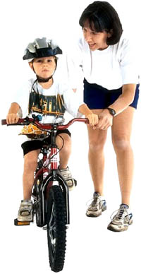 developmental milestones of biking: Boy on bike next to mom.