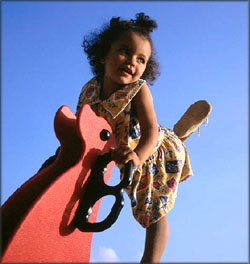 Little girl on playground with blue sky. 