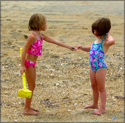 Reaching the milestone of cooperative playing: Two girl playing together on the beach. 