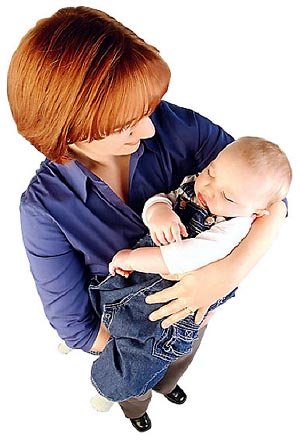 Mom carrying sleeping baby in her arms.