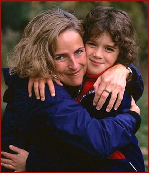 Mother and daughter in affectionate hug outside.