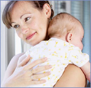 Mother carrying her little infant baby over her shoulder.