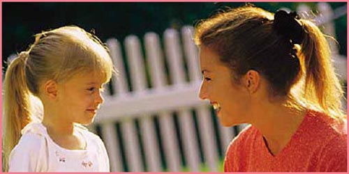 Mother and her girl looking happily at each other in the morning light